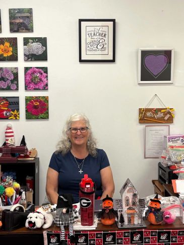 Woman smiling behind decorated desk with Halloween items.