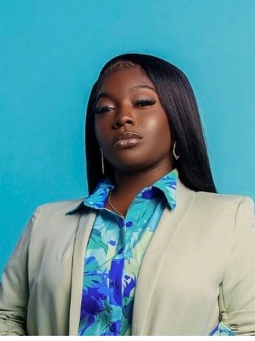 Confident woman in a beige blazer and floral shirt against a blue background.