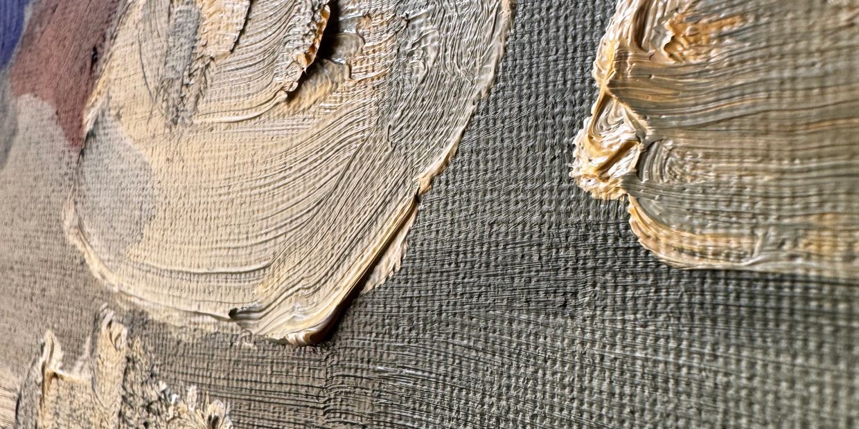 Close-up of textured beige paint on canvas.