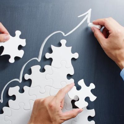 Hands completing a puzzle with an upward arrow.