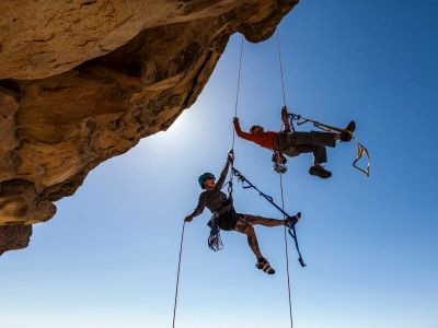 Two climbers hanging on ropes under a rock overhang.