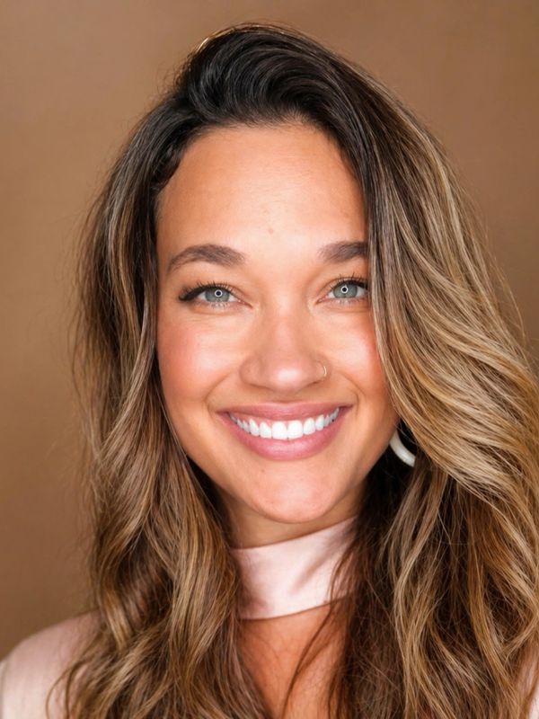 Close-up of a smiling woman with blue eyes and wavy hair.
