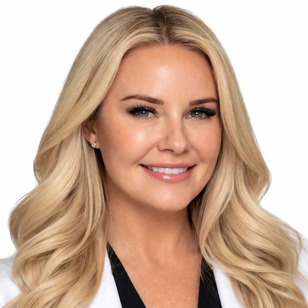 Professional portrait of a smiling blonde woman with long wavy hair.