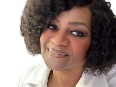 Portrait of a smiling woman with curly hair wearing a white blouse.