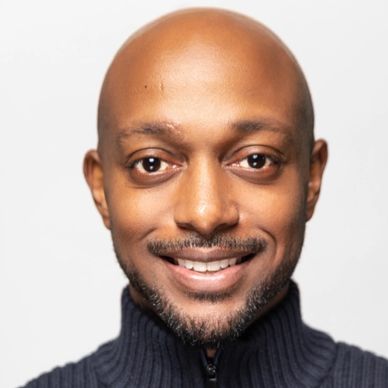 Smiling man in a dark knitted sweater with a zipper, posing against a plain background.