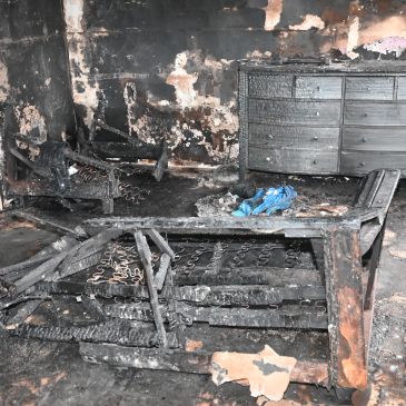 Burned and charred furniture in a fire-damaged room.