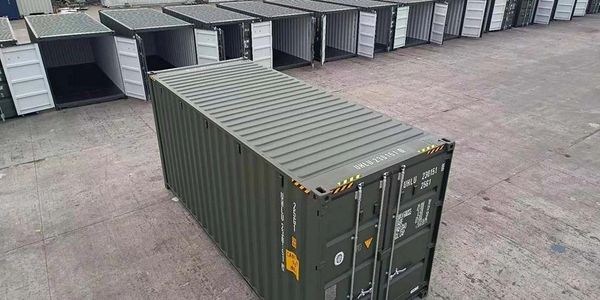 A green shipping container in front of multiple open containers.