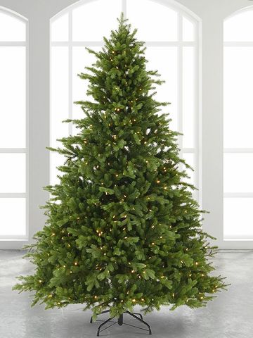 Lit artificial Christmas tree in front of windows.
