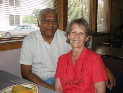 Older couple sitting and smiling indoors.