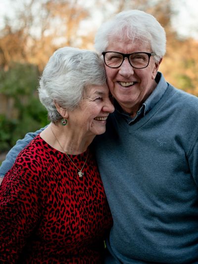 A senior couple stands leaning into each other and smiling. Photo credit: Joe Hepburn.