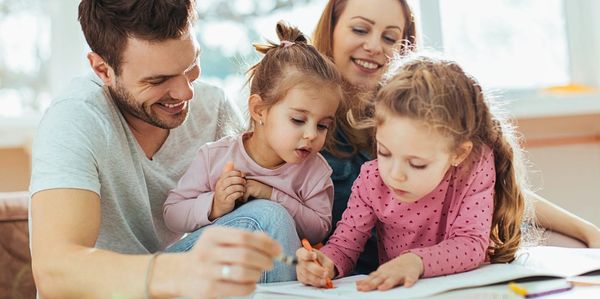 Family coloring together: father, mother, and daughters engaged in a coloring activity.