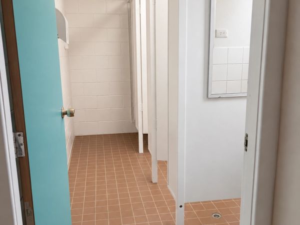 Empty public restroom with turquoise door and brown tiled floor.
