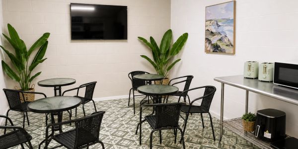 A modern break room with tables, chairs, and a TV.