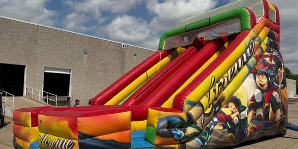 Colorful inflatable slide with vibrant graphics set outdoors on a sunny day.