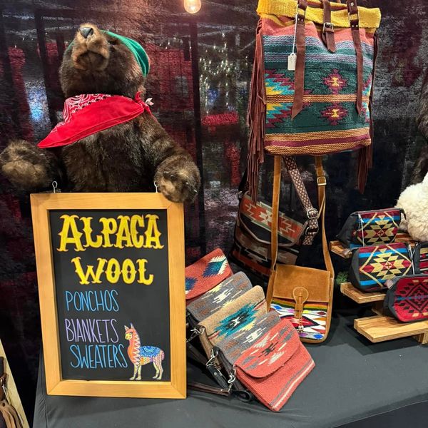 Stuffed bear with alpaca wool products and a sign listing ponchos, blankets, and sweaters.