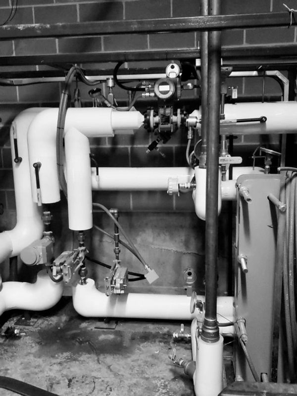 Complex industrial piping and valves setup in a mechanical room.