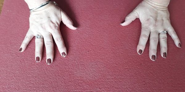 Two hands with rings on a textured red surface.