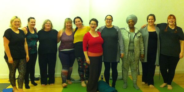 Group of women standing together in a yoga or fitness studio, smiling and relaxed.
