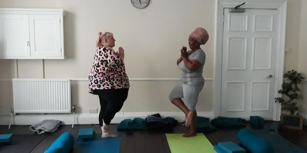 Two women practicing yoga together in a calm indoor setting.