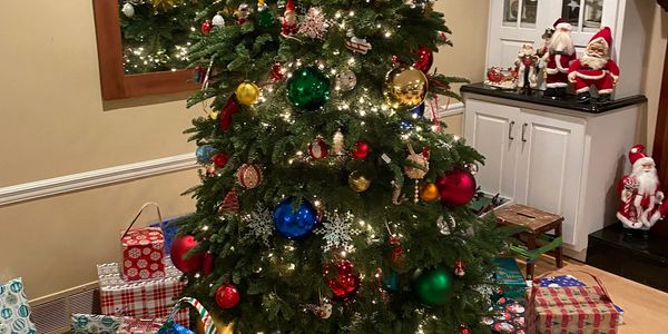 Interior Christmas tree with presents and Santas in the background.