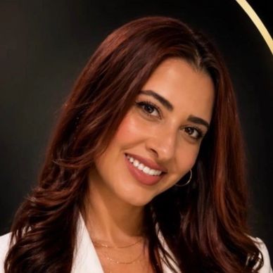 Smiling woman with long brown hair against a dark background.