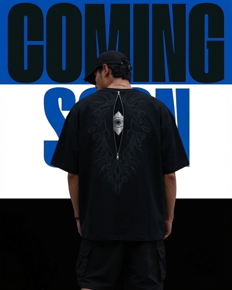 Person wearing black shirt with zipper and eye design on back.