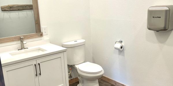 Bathroom with a vanity, toilet, and hand dryer, from left to right respectively.