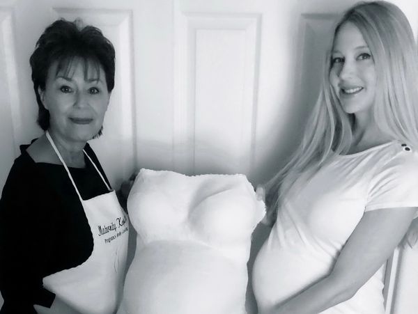 Two women holding a plaster belly cast of a pregnant belly.