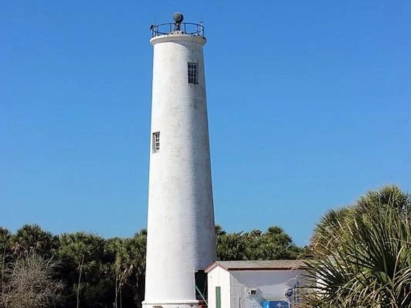 Tall white lighthouse against clear blue sky.
