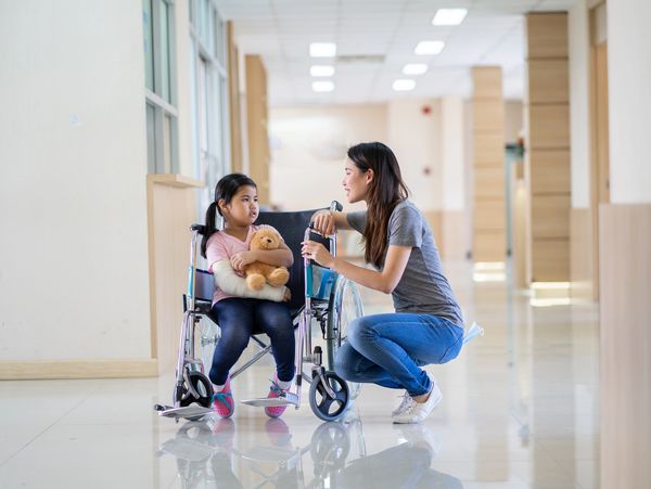 A woman on a wheelchair interacting with a small child.