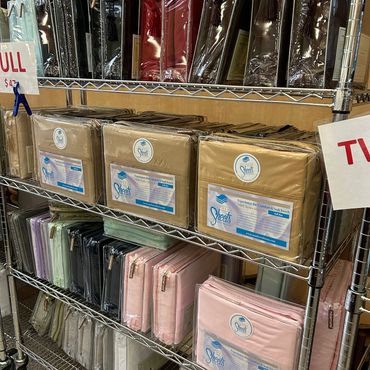 Shelves displaying various colors of packaged bedsheets for sale.