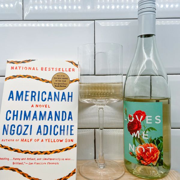 Americanah book with a glass of "Loves Me Not" wine.