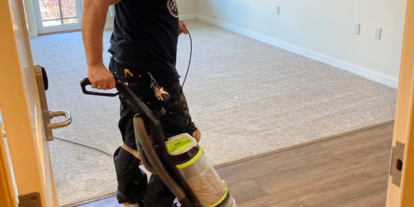 Bobby vacuuming vynl floor in an empty room with carpet in the background.