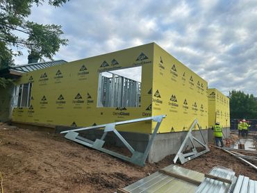 Construction site with a building framed and wrapped in yellow sheathing.