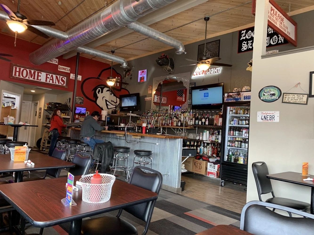 Cozy bar area with tables, stools, and sports-themed decor.