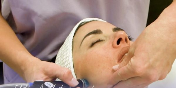 A woman receiving a facial massage with eyes closed in a spa.