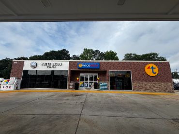 Front view of a convenience store with multiple brand signs.