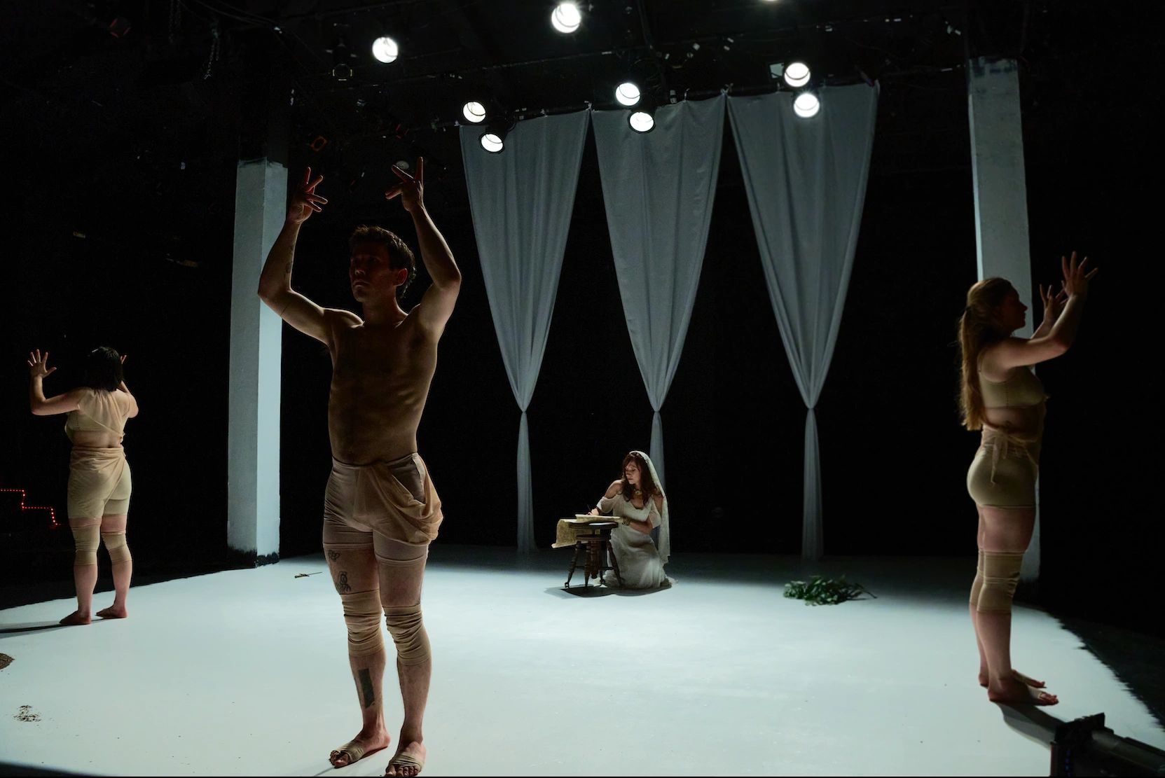 Contemporary dance performance with expressive hand movements and a seated writer.