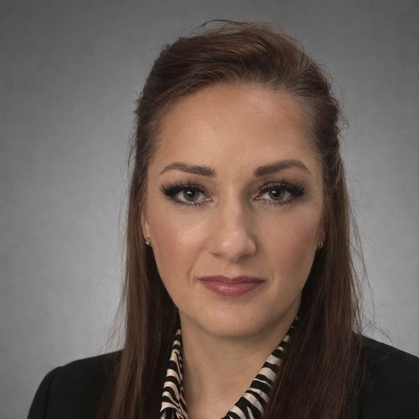 Professional woman with long brown hair and subtle makeup in business attire.