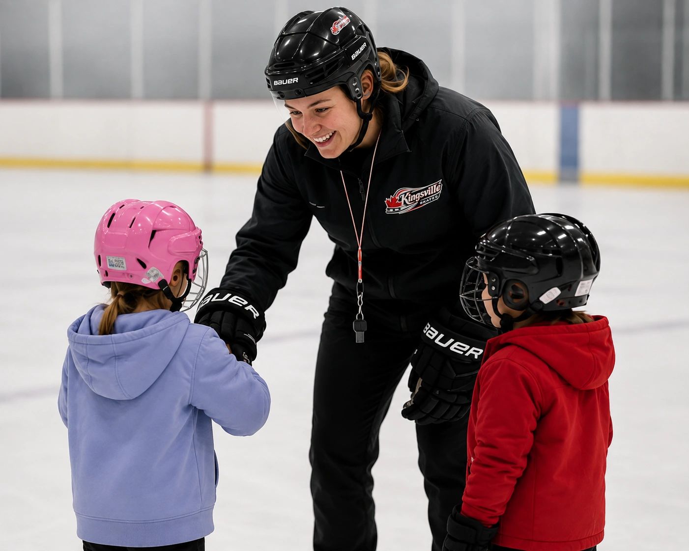 Hockey coach interacting with two kids on ice rink.