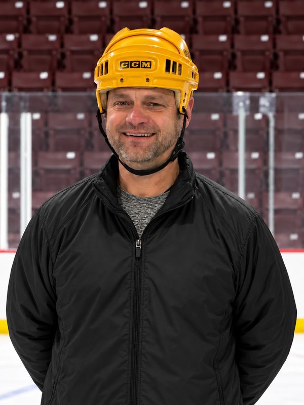 Man wearing a yellow hockey helmet and black jacket on ice rink.
