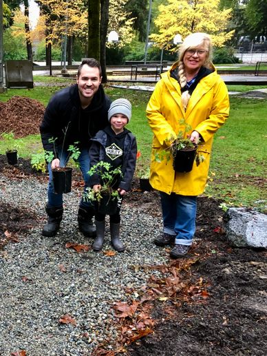 Three generations planting trees in a park during autumn.