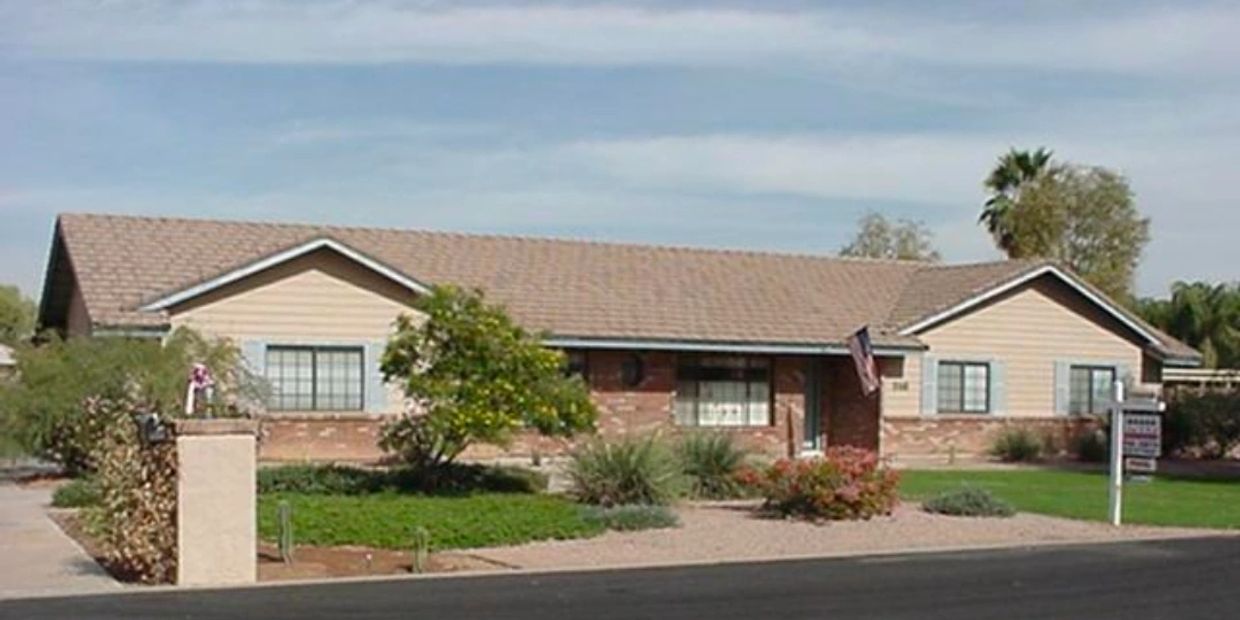 Single-story suburban house with a well-maintained garden and an American flag.