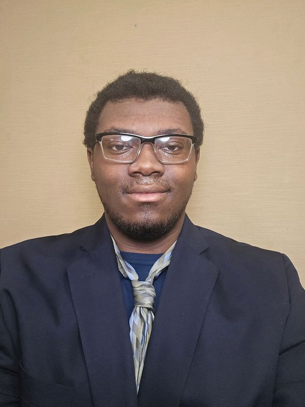 Man wearing glasses, a suit jacket, and a loosely tied necktie.