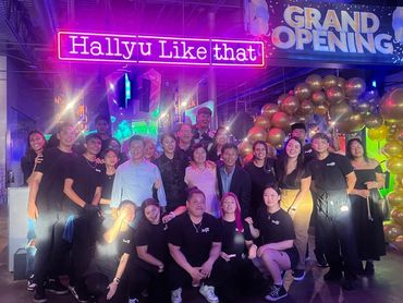 The restaurant staff smiling in front of a banner that reads, "Grand Opening."