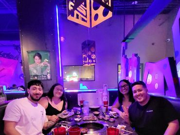 A group of people smiling at their table full of food and drinks.