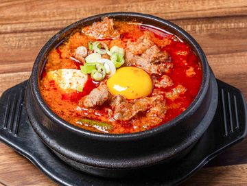 Tofu stew with beef brisket in a spicy broth bowl.