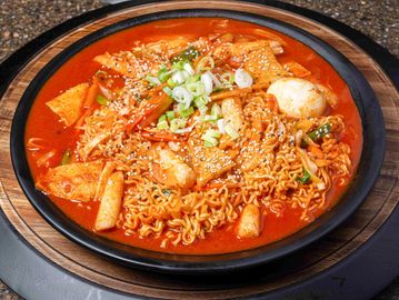 Ramen mixed with veggies and hardboiled egg in large plate.