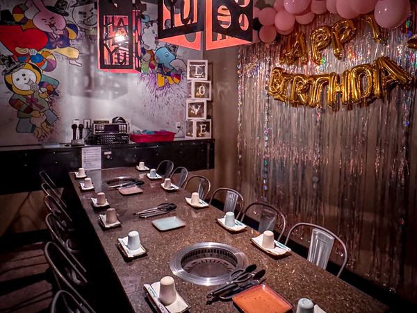 A private karaoke room with birthday decorations. The table has two built-in grills and seats 12.