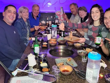 A group of people smiling at their table with two built-in smokeless grills.
